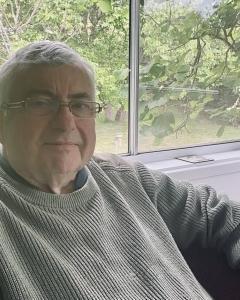 Philip&#039;s portrait with greenery in the background.
