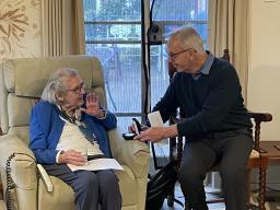 A man presents a medal to a woman seated.