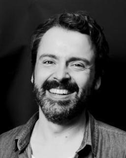 Black and white photograph of Scott McKinnon with a dark background.