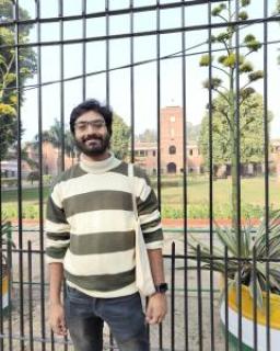 Anonyo smiling in front of a gate