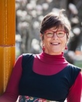 Photograph of Dr Julie Rickwood, wearing red glasses and earrings.